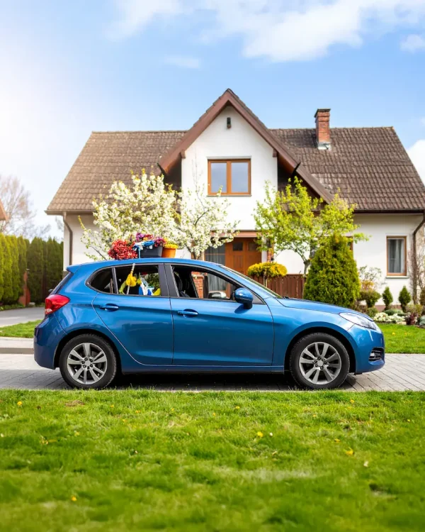 Firefly_Realistic photo of a small, well-maintained blue hatchback car parked in front of an 547043 kopia